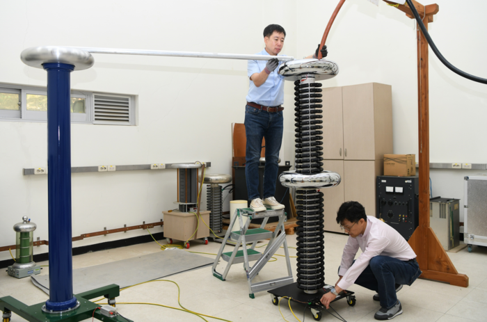 이상화 표준연 책임연구기술원(위)과 이형규 양자전기자기측정그룹장이 초고압 직류 송전 전압(HVDC)을 측정하기 위해 직류 초고압 분압기를 조작하고 있다.